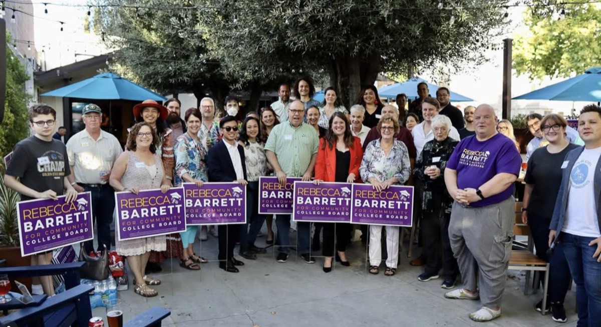 Supporters gather on a tree-shaded patio holding purple Rebecca Barrett for Community College Board signs